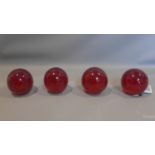 Four cranberry glass paperweights