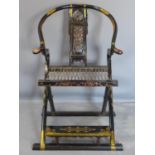 A 19th century Chinese ebonised and brass clad round back folding armchair, with pierced back