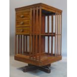 An early 20th century inlaid mahogany revolving bookcase, the cross-banded top above three short
