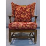 An oak winged back armchair, with floral upholstered cushions, raised on square legs and castors,