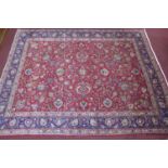 A large Persian Tabriz carpet, stylised floral motifs on a red ground, within stylised floral border