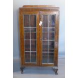 An early 20th century oak bookcase, with leaded glass doors, on cabriole feet, H.125 W.67 D.25cm