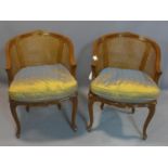 A pair of French Louis XV style walnut bergere armchairs, with caned seats and backrests, raised