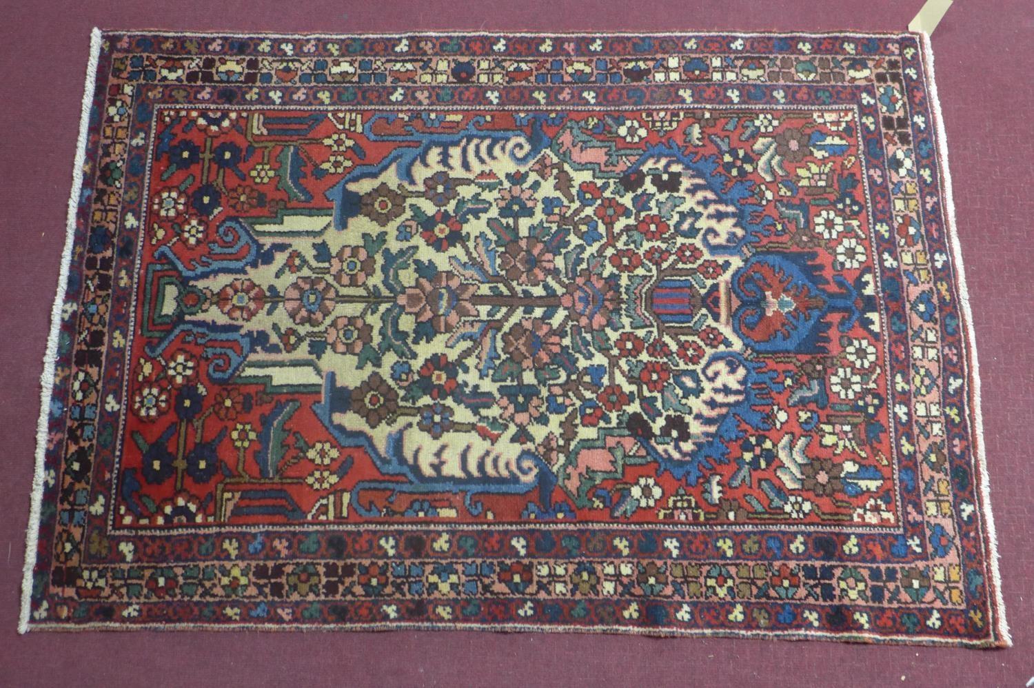 A Central Persian Bakhtiari rug, repeating stylised floral motifs on an ivory field, within stylised