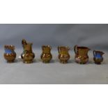 A collection of six copper lustreware ceramic jugs of varying size, with floral decoration,