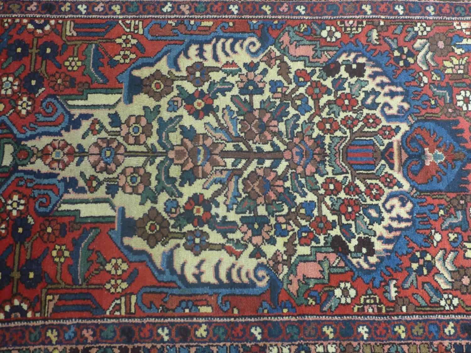 A Central Persian Bakhtiari rug, repeating stylised floral motifs on an ivory field, within stylised - Image 2 of 5