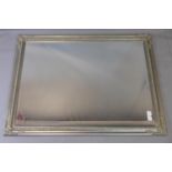 A contemporary wall mirror with silver painted floral decorated frame and bevelled glass plate,