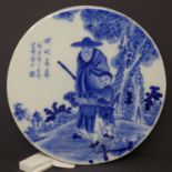 A Chinese circular blue and white porcelain plaque, decorated with an elderly man and child in a