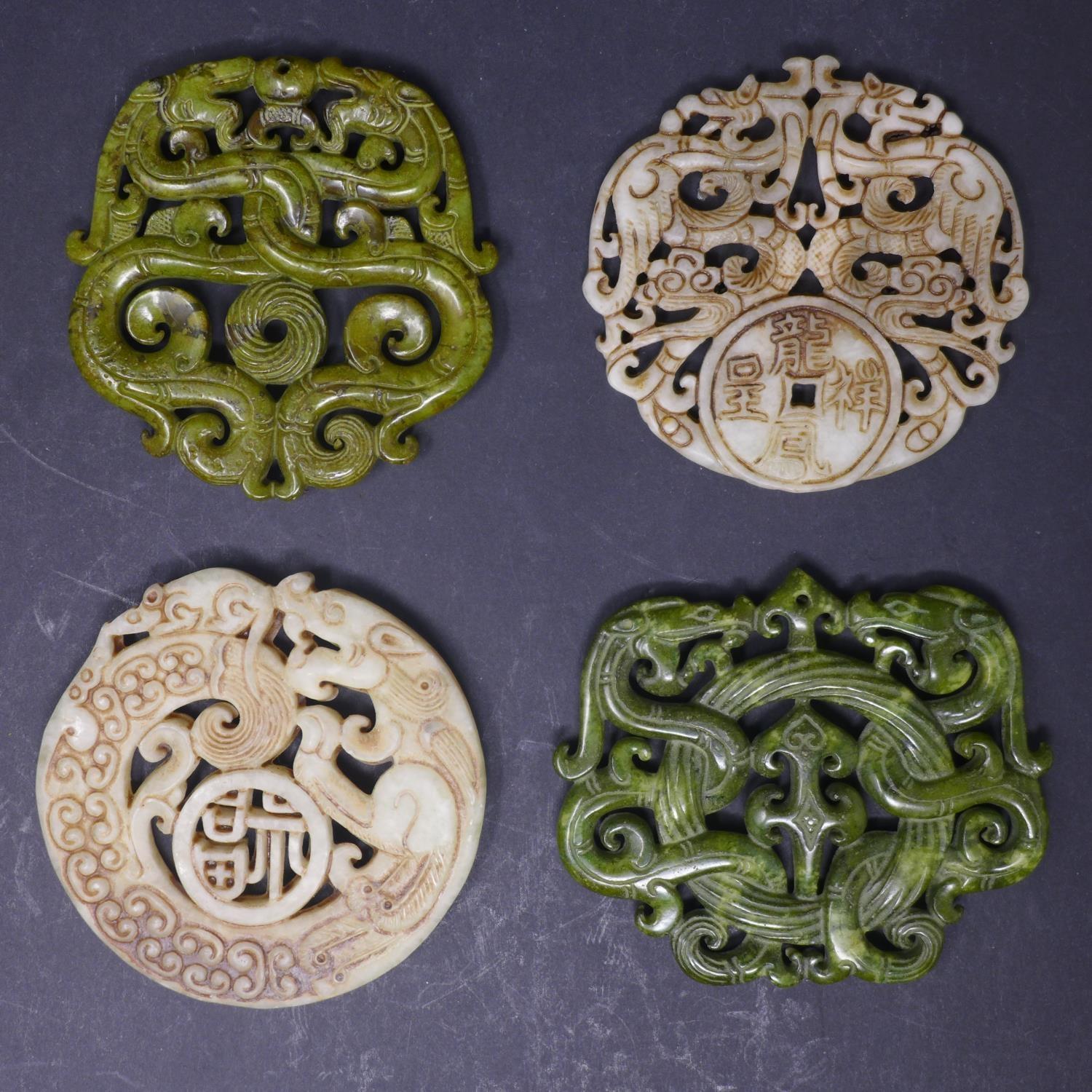 Four Chinese hardstone amulets, with pierced decoration of dragons, Diameter 7cm (largest) (4)