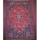 A Persian Qashqai Kashkuli rug, central medallion with floral and geometric motifs on a red
