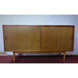 A mid 20th century teak sideboard by Hille, London, with sliding doors, raised on tapering legs, H.