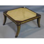 A Regency style footstool in the manner of William Kent, with caned seat, having gilt detailing,
