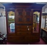 A large 20th century walnut breakfront wardrobe, with two central cupboard doors with carved