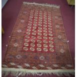 An Afghan Bokhara rug, with elephant pad motifs on a rouge field, within stylised geometric borders,