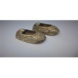 Two 19th century Continental silver ashtrays in the form of shoes, repousse embossed with flowers,