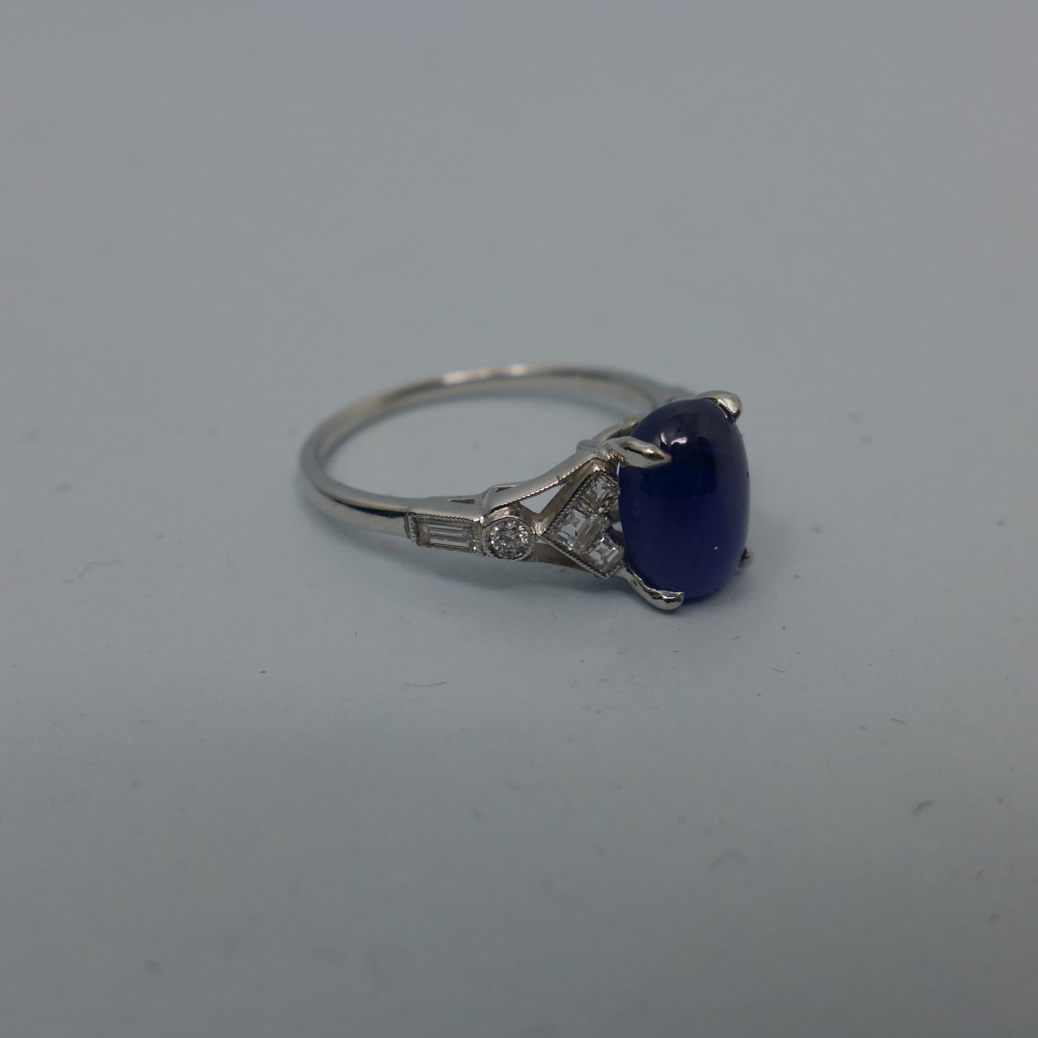 A platinum ring set with translucent blue oval double cabochon sapphire and 10 colourless