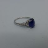 A platinum ring set with translucent blue oval double cabochon sapphire and 10 colourless