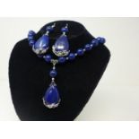 A lapis lazuli and silver plated necklace with serpeant head mounts and with pendant having floral