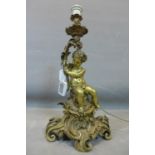 A large gilt bronze figural table lamp, in the Roccoco style, with cherub seated on elaborate C-