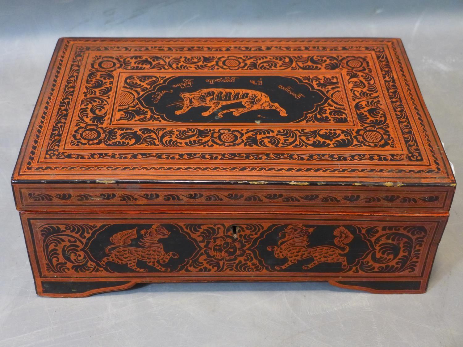 Large Burmese lacquered box richly decorated on the cover with a tiger and a Burmese inscriptions,