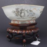 A Chinese porcelain bowl with a landscape design of a lake, trees, buildings and a bridge, with a