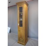 A large pine pedestal cupboard, with moulded cornice above glazed door, on pedestal base, H.229 W.50