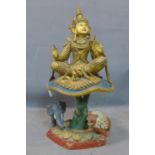 A large Southeast Asian (possibly Siamese) gilt painted deity seated on a polychrome painted