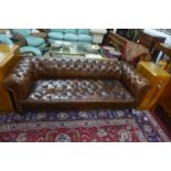 A Victorian brown leather button back and stud bound Chesterfield Sofa, raised on turned legs, H.