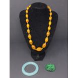 A group of Chinese jewels including a jade bracelet, a hard stone pendant and amber neckless