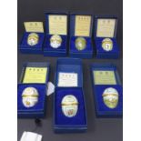 A collection of seven boxed Halcyon Days enamel Easter eggs, to include 1984-1990, each with