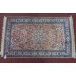 A pure silk Persian Kirman rug, central floral medallion with stylised motifs on a pink ground,