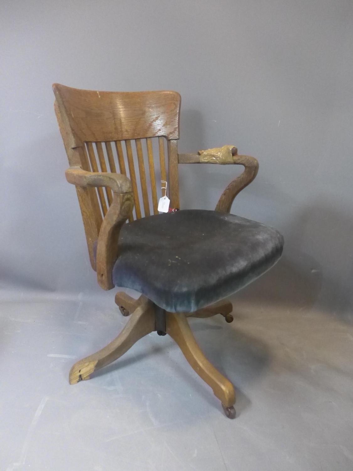 An early 20th century oak swivel desk chair, raised on ceramic castors, (one foot broken - needs