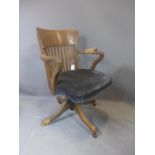 An early 20th century oak swivel desk chair, raised on ceramic castors, (one foot broken - needs