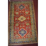 A Russian Kazakh rug, three central diamond medallions and geometric motifs on a rouge field, within