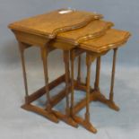 A walnut nest of three tables, with quarter veneered tops with serpentine fronts, raised on