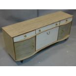 A 1960's serpentine fronted sideboard, with one long and two short drawers, above central drinks
