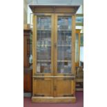 A 19th century Arts & Crafts oak cabinet with moulded cornice above two leaded glass doors with