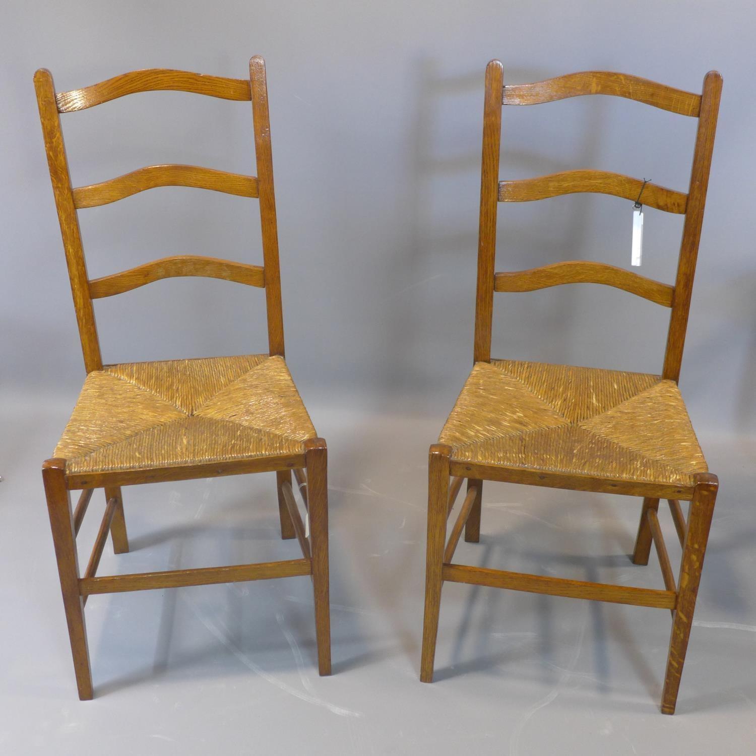 A pair of oak ladderback chairs with rush seats