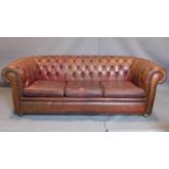 A three seater leather Chesterfield sofa, with button back upholstery, heavily worn
