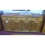 A mid 20th century Ercol teak sideboard, with four short drawers and two pairs of double doors, on