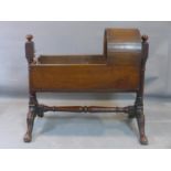 A 19th century mahogany crib, on turned supports and floral carved scrolling feet, H.90 W.56 D.100cm