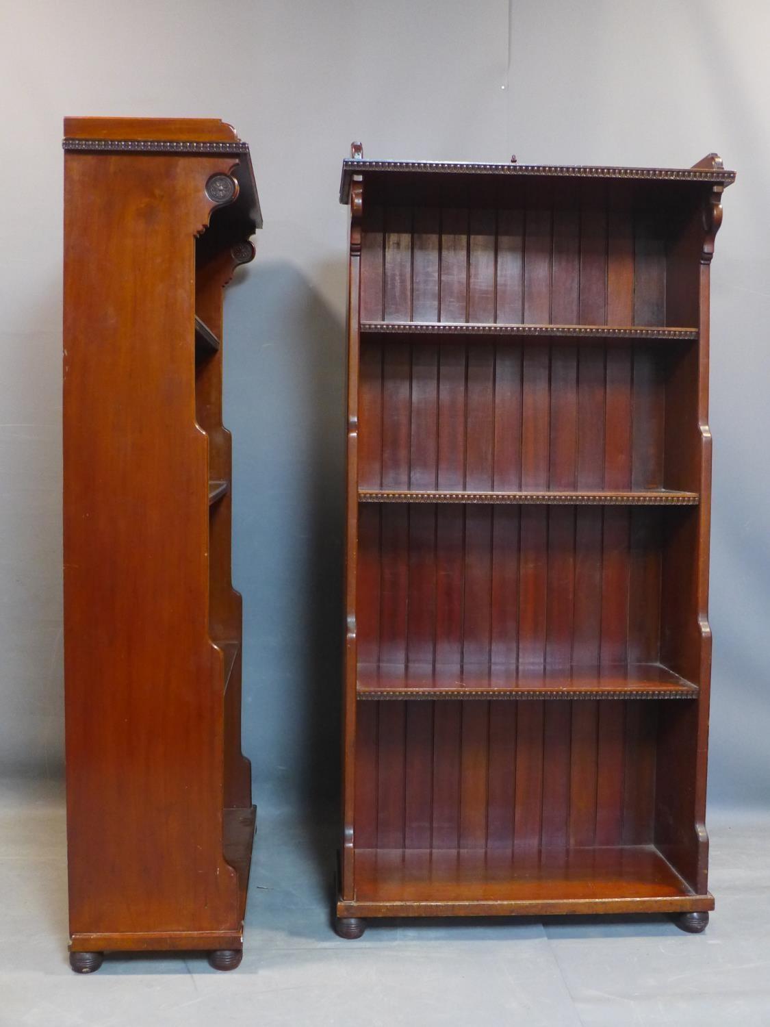 A pair of Victorian walnut open waterfall bookcases with egg and dart edges, having floral carving