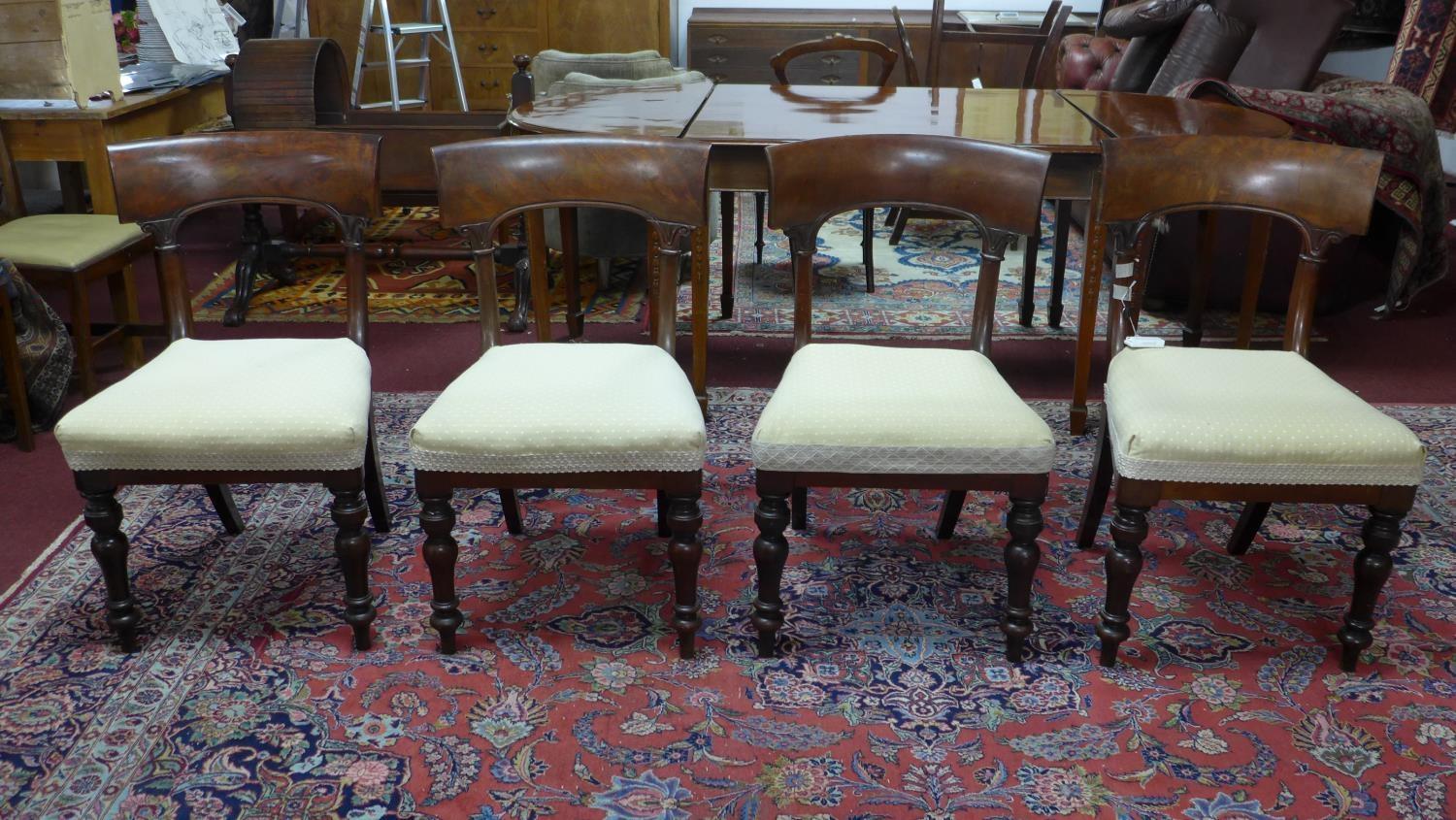 A set of four mahogany William IV dining chairs, with cream upholstered seats, on turned legs, label