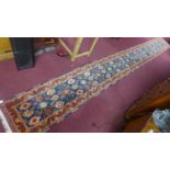 A Turkish hand-made runner, with root paint, having repeating petal motifs on a dark blue ground,
