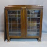 An early 20th century oak glazed bookcase, with two leaded glass doors enclosing adjustable shelves,