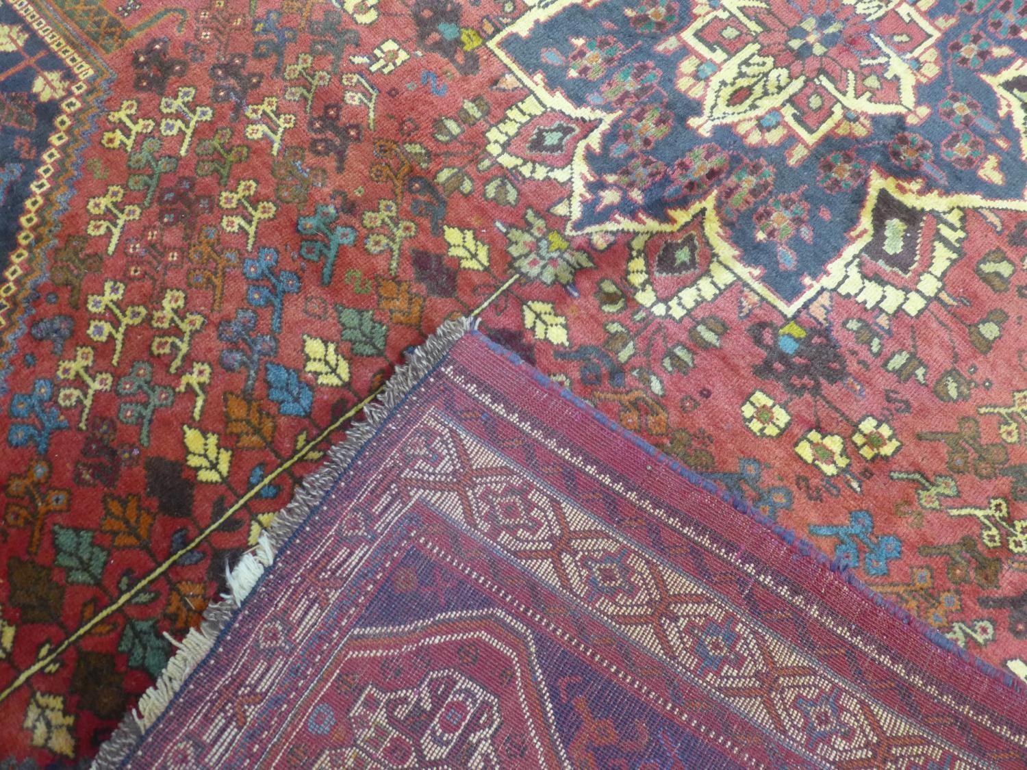 A Persian Qashqai carpet, central floral medallion and stylised petal motifs on a rouge field, - Image 5 of 5