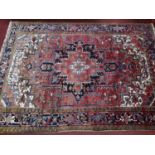 A Persian Heriz carpet, central floral medallion and stylised floral motifs on a rouge ground,