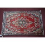 A North West Persian Mahal rug, central floral medallion with repeating petal motifs on a rouge