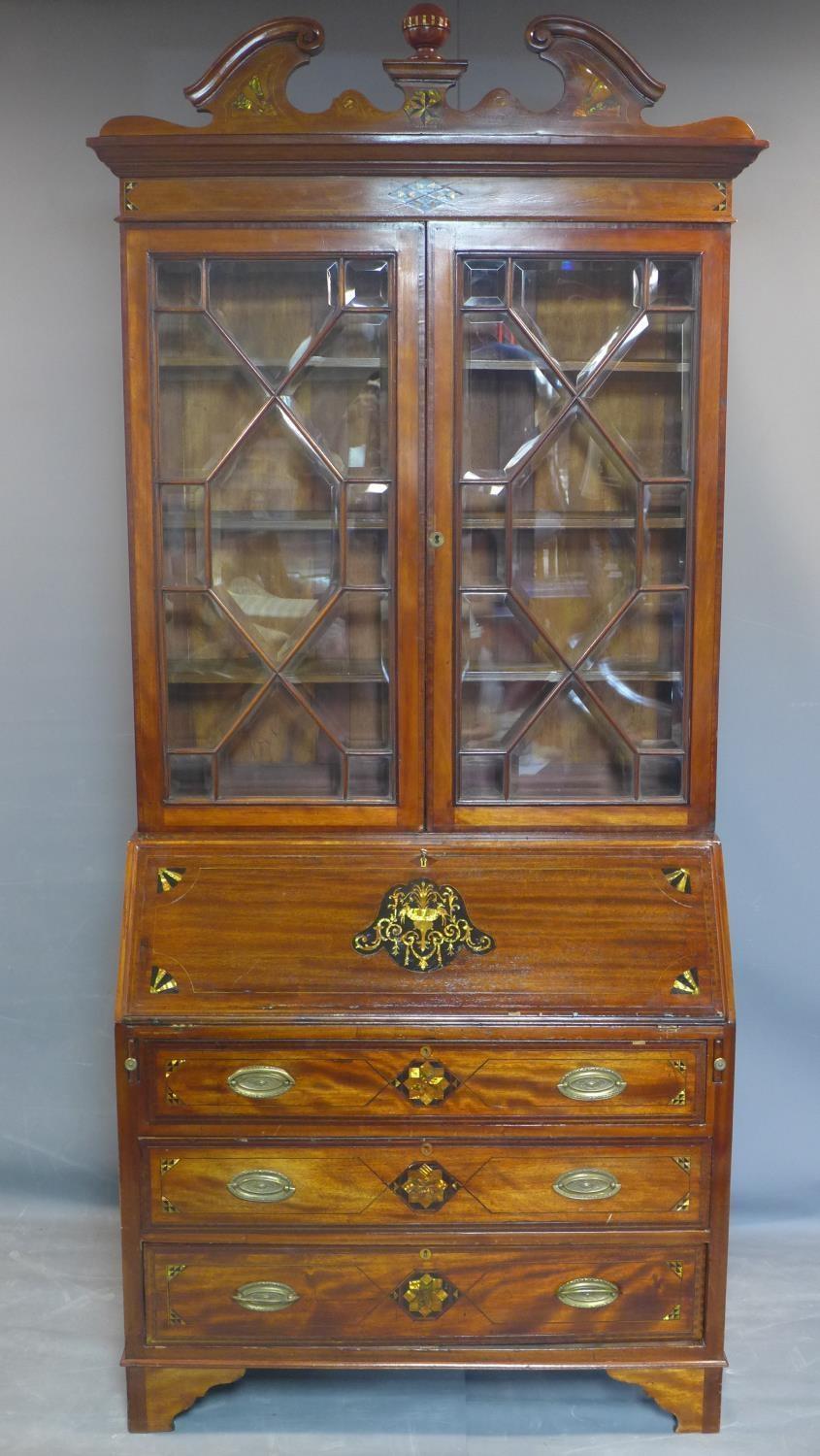 A 19th century inlaid mahogany bureau bookcase, the broken arch pediment above two astragal glazed