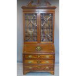 A 19th century inlaid mahogany bureau bookcase, the broken arch pediment above two astragal glazed